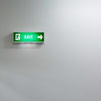 shutterstock 234875881 green fire exit sign against an indistinct soft white background