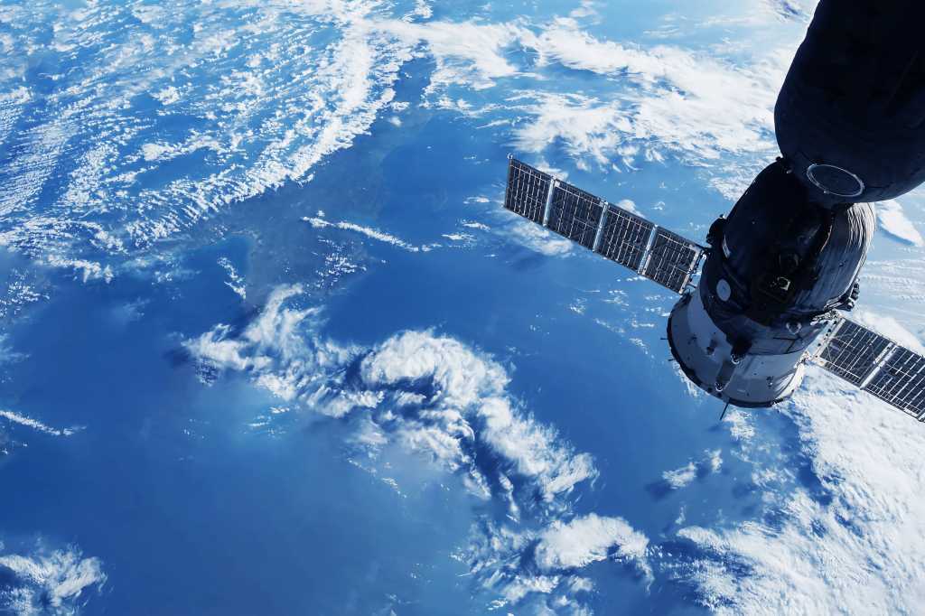 shutterstock 2291065933 space satellite in orbit above the Earth white clouds and blue sea below